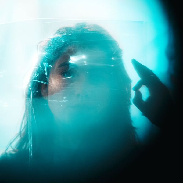 Person meditating peacefully with an aqua-colored aura effect.